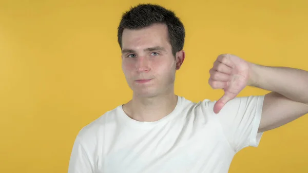Homem casual Gesturing polegares para baixo isolado no fundo amarelo — Fotografia de Stock