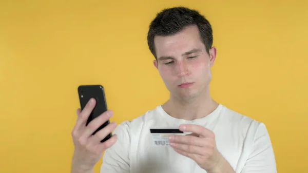 Compras en línea por el hombre casual a través de Smartphone aislado en el fondo amarillo —  Fotos de Stock
