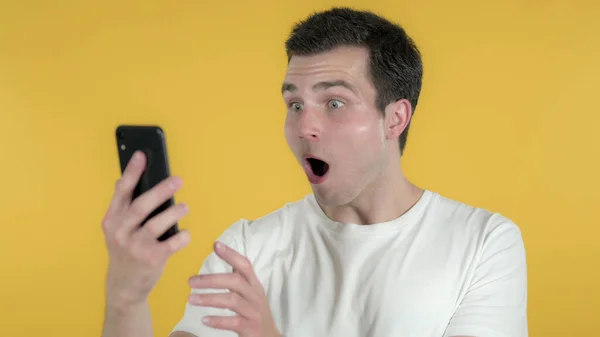 Impresionado hombre casual usando Smartphone aislado sobre fondo amarillo — Foto de Stock