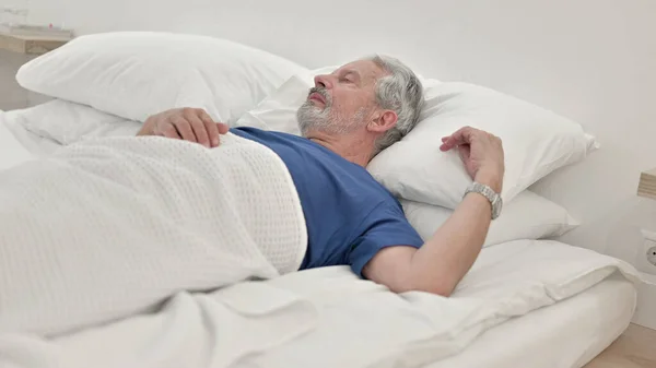 Zamyślony starszy człowiek leżący w łóżku — Zdjęcie stockowe