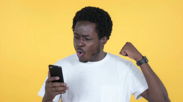 Başarı kullanarak Smartphone izole sarı arka plan üzerinde süre için rahat Afrika heyecanlı adam — Stok fotoğraf