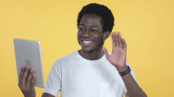 黄色の背景に隔離されたタブレットを介してカジュアルアフリカ人男性によるビデオチャット — ストック写真