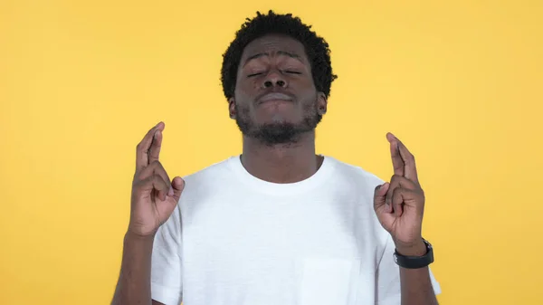 Prst křížený pro štěstí podle ležérní africký muž na žlutém pozadí — Stock fotografie