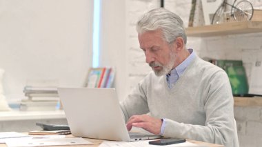 Dizüstü bilgisayarda çalışan yaratıcı kıdemli yaşlı adam