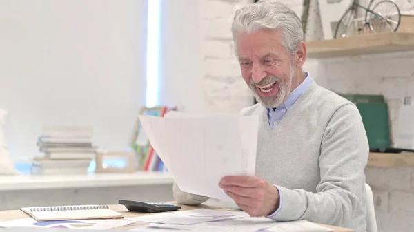 Starší muž slaví úspěšnou smlouvu při čtení dokumentů — Stock fotografie