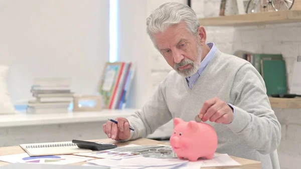 Vieil homme âgé mettant pièce de monnaie dans la tirelire — Photo