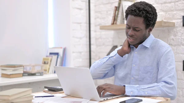 Ung afrikansk man som har ont i nacken medan han arbetar — Stockfoto