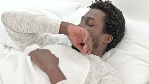 Νεαρός Αφρικανός που βήχει ενώ κοιμάται στο κρεβάτι — Φωτογραφία Αρχείου