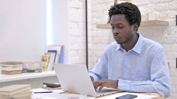 Ung afrikansk man som arbetar på laptop — Stockfoto
