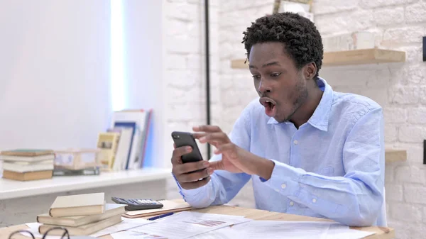 Jovem Africano Surpreso com os resultados no Smartphone — Fotografia de Stock