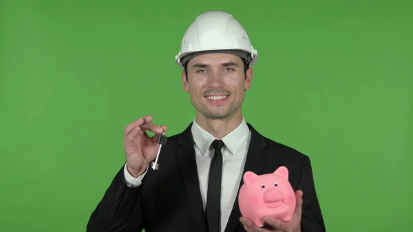 Vidám mérnök Holding kulcs és Piggy Bank, chroma key — Stock Fotó