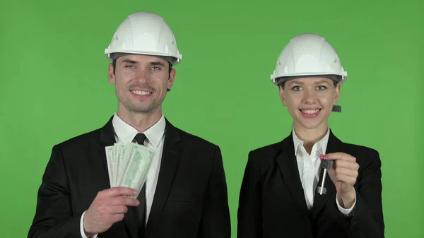 Young Male and Female Engineer Holding Key and Dollars, Chroma Key — Stock Photo, Image