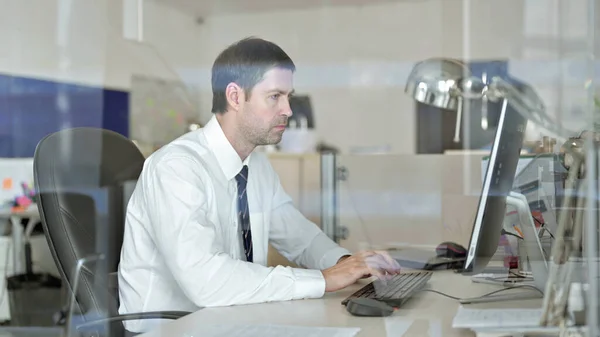 Ofiste Bilgisayar üzerinde çalışan hırslı Orta Yaşlı İşadamı — Stok fotoğraf