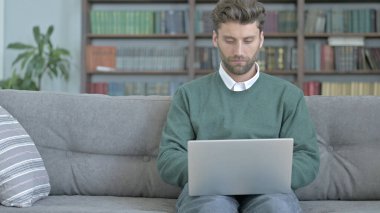 Ciddi Genç Adam Kanepede Oturan ve Bir Laptop Üzerinde Çalışma