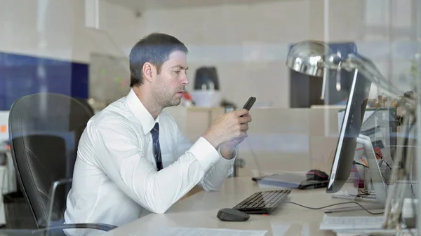 Empresario ambicioso de mediana edad usando su teléfono inteligente en la oficina — Foto de Stock