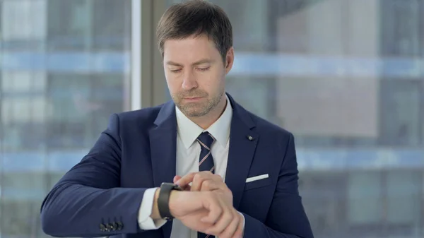 Ambicioso hombre de negocios de mediana edad usando reloj inteligente —  Fotos de Stock