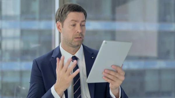 Fröhlicher Geschäftsmann mittleren Alters beim Videochat auf dem Tablet — Stockfoto