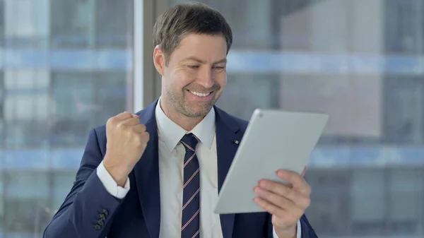 Geschäftsmann mittleren Alters reagiert auf Erfolg auf dem Tablet — Stockfoto