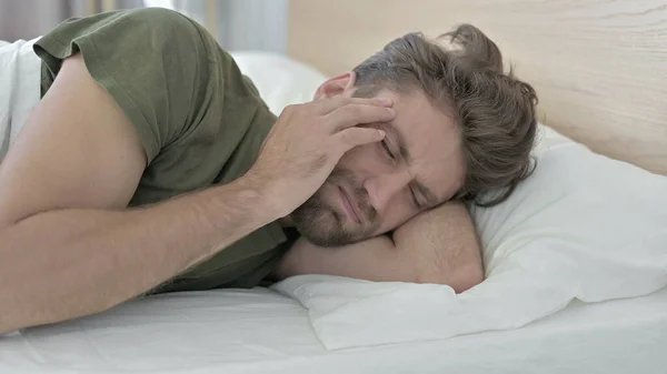 Primer plano del joven con dolor de cabeza en la cama mientras duerme —  Fotos de Stock