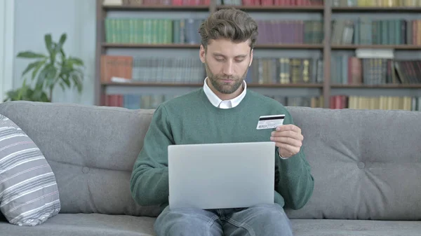 Man zit op de bank en zingen Credit Card, Online winkelen — Stockfoto