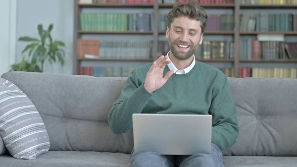 Человек сидит на диване и видео Звонок через ноутбук — стоковое фото