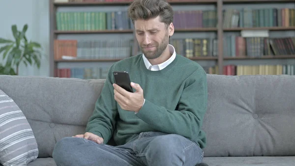 Ongelukkige jonge man controleren van zijn telefoon en het gevoel verslagen — Stockfoto