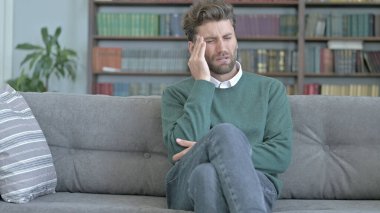 Stresli Genç Adam Kanepede oturan ve Baş Ağrısı olan