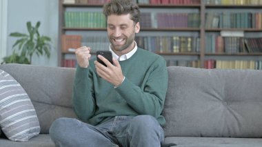 Genç Adam Akıllı Telefonunda Geziniyor ve Kutluyor