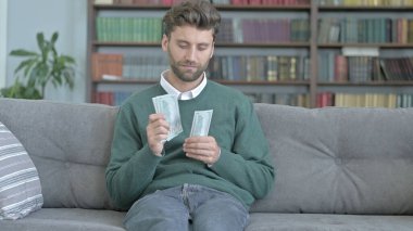 Genç Adam Kanepede Oturur ve Para Sayma