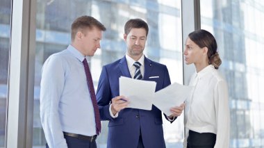 Businessman Explaining on Documents to his Assistants in Office