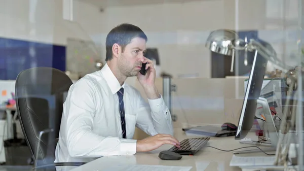 Empresario ambicioso de mediana edad que habla en su teléfono inteligente en la oficina —  Fotos de Stock