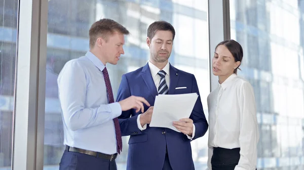Бизнесмен и его помощники обсуждают документы в офисе — стоковое фото