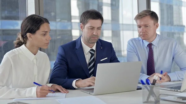 Empresario de mediana edad usando el ordenador portátil con el equipo —  Fotos de Stock