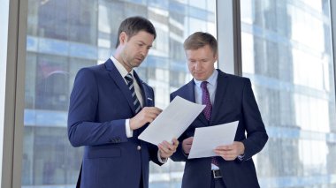 İki Orta Yaşlı İşadamı Yönetim Kurulu Ofis Penceresine Karşı Belgeleri Okuyor