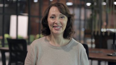 Yaşlı Kadın Gülümsüyor ve İş Yerinde Kameraya Bakıyor