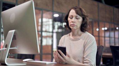 Yaşlı Kadın İş Yerinde Akıllı Telefon Kullanıyor