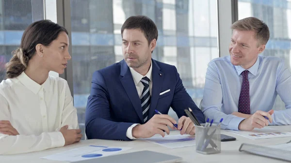 Бизнесмен среднего возраста беседует со своими помощниками на рабочем столе — стоковое фото