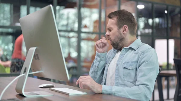 Kranker junger Mann hustet während der Arbeit am Computer — Stockfoto