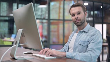 Genç Adam İş Yerinde Otururken Kameraya Bakıyor