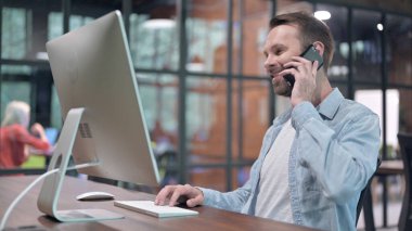Genç adam iş yerinde konuşuyor.