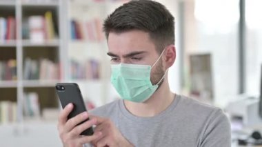 Akıllı telefon kullanan Yüz Maskeli Genç Adam Portresi 