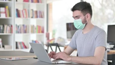 Laptop kullanan Yüz Maskeli Tedbirli Genç Adam