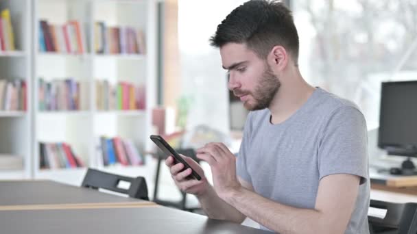 Komoly fiatalember használja okostelefon az irodában — Stock videók
