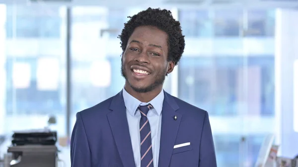 Překvapený africký podnikatel se usmívá na kameru — Stock fotografie