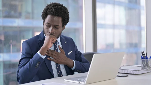 Zieke Afro-Amerikaanse zakenman met hoesten tijdens het gebruik van Laptop — Stockfoto