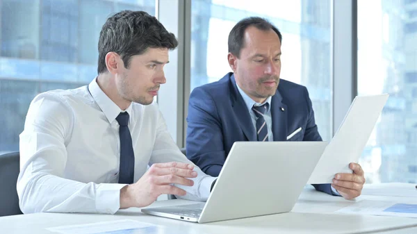 Empresários discutindo dados sobre laptop e documentos — Fotografia de Stock