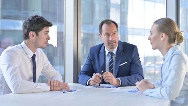 Empresário de meia-idade conversando com assistentes em Boardroom Desk — Fotografia de Stock