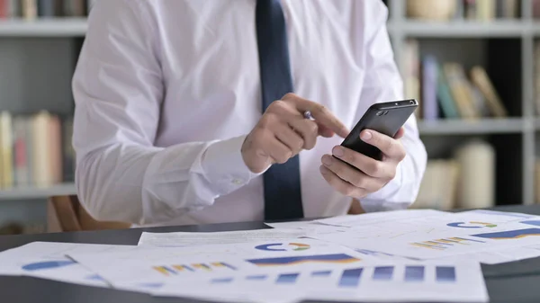 Nahaufnahme eines Geschäftsmannes mit dem Smartphone auf dem Bürotisch — Stockfoto