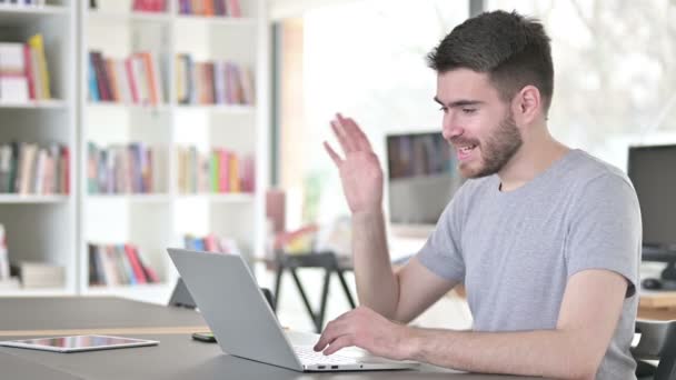 Chat vidéo sur ordinateur portable par Jeune homme au bureau — Video