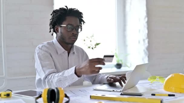 Erfolg beim Online-Bezahlen durch afrikanischen Architekturingenieur am Laptop im Büro — Stockvideo
